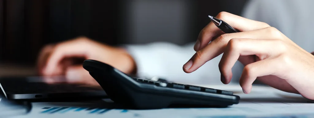 Close-up of a person working on a calculator, emphasizing the process of reviewing or calculating credit report details.