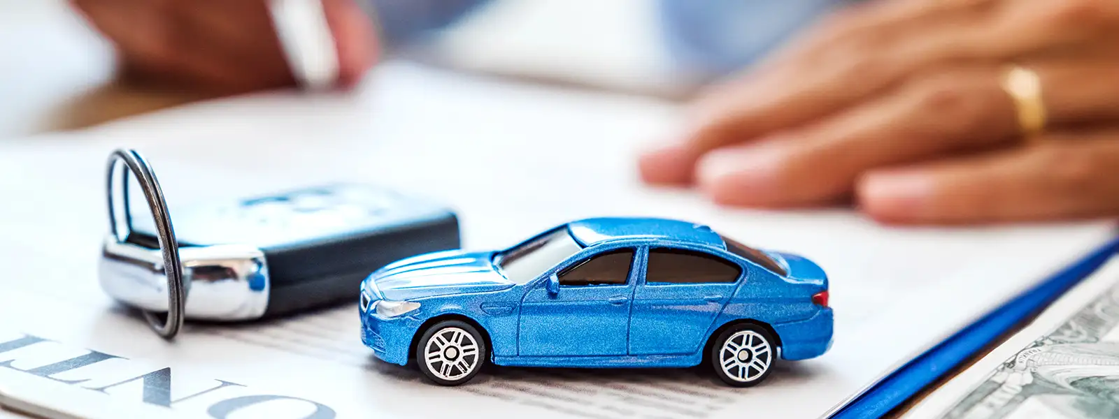 Small blue toy car on a table in a light room, symbolizing the process of getting a car loan, especially for those with bad credit.