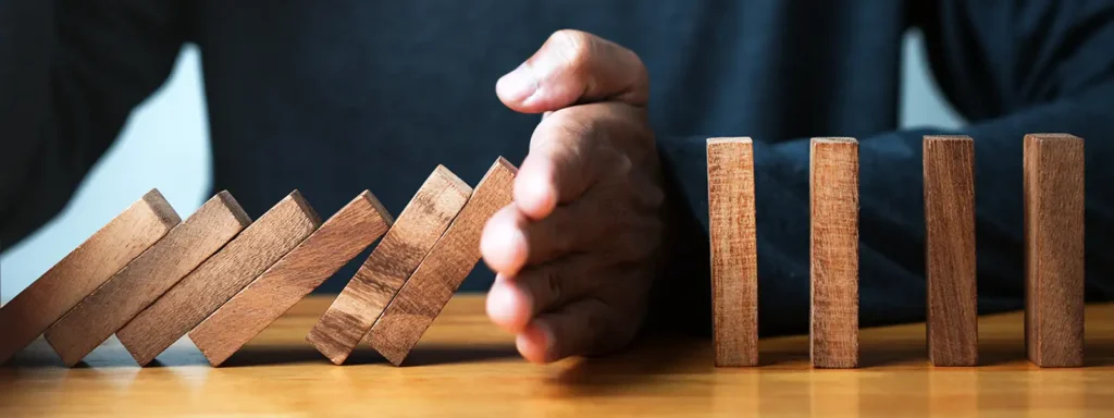 Man holding a row of wooden bricks, with some already fallen, symbolizing the concept of financial instability or bankruptcy, but emphasizing that bankruptcy doesn't mean bad credit forever.