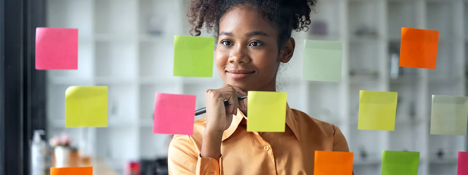 Young woman writing on pieces of paper that resemble memory cards, symbolizing the process of understanding and tracking credit scores.